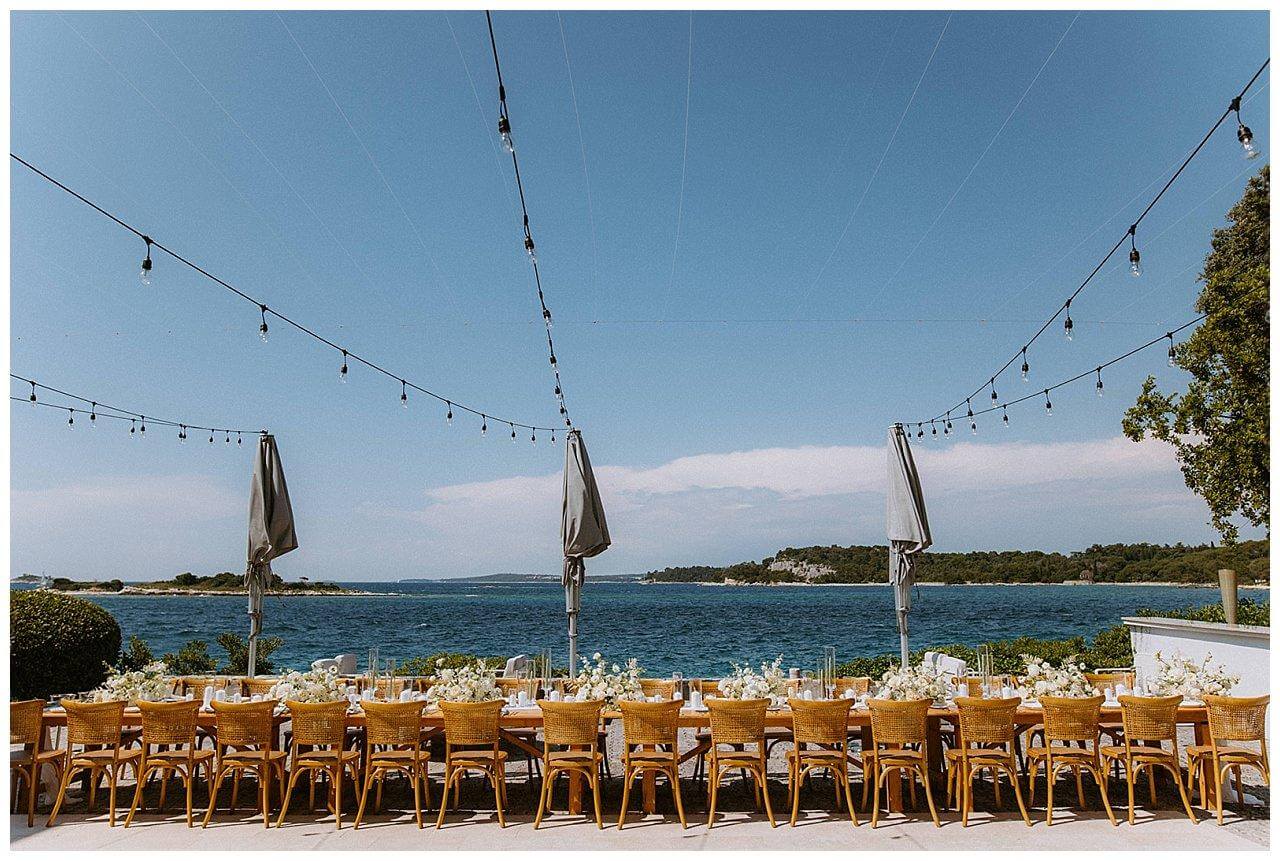 Brauner Holztisch mit weißer Dekoration mit dem Blick aufs Meer bei einer Hochzeit in Istrien Kroatien