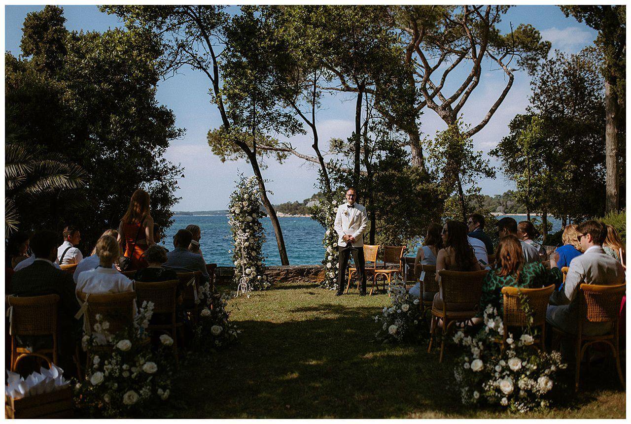 Freie Trauung mit den Blick aufs Meer und Traubogen aus blättern und weißen Rosen bei einer Hochzeit in Istrien Kroatien