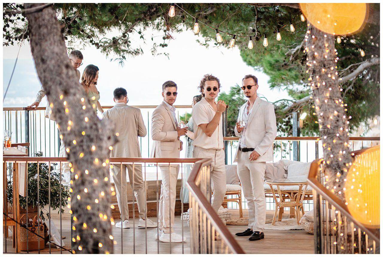 Gäste des Brautpaares auf einer Terrasse mit dem Blick auf Meer bei einer Hochzeit in Kroatien