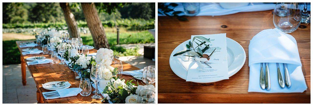 Tischdekoration in weiß und dunkelgrünen Blättern auf einen Dunkel braunen Tisch bei einer Hochzeit in einer Finka in Istrien Kroatien