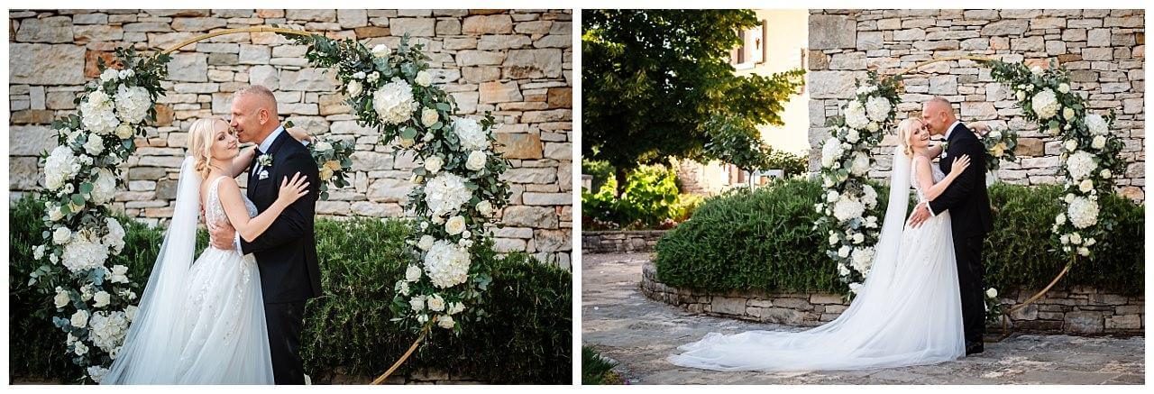 Brautpaar vor Traubogen aus Holz mit weißen Rosen bei ihrer Hochzeit in einer Finka in Istrien Kroatien