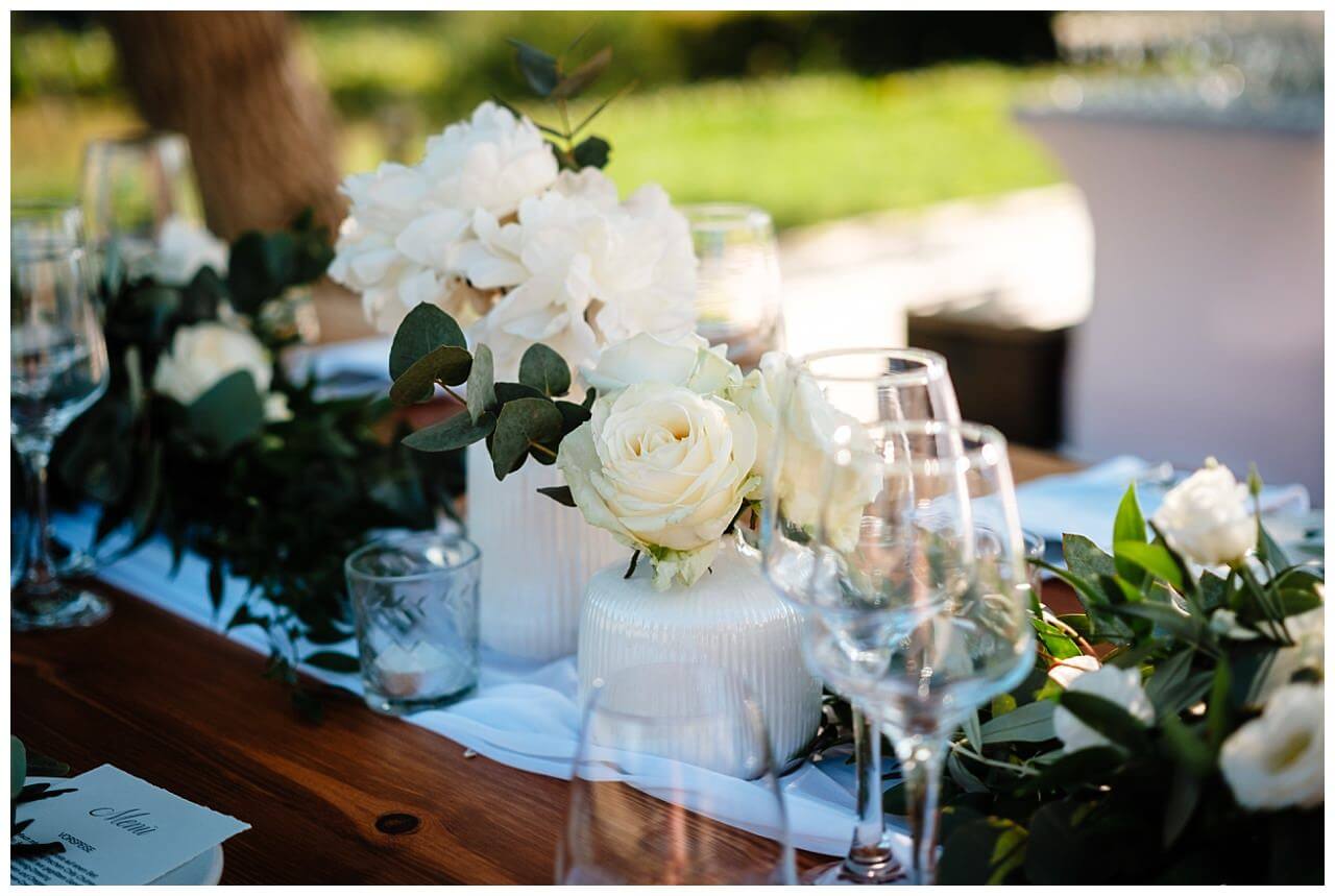 Tischdekoration für Hochzeit in weiß mit weißen Rosen und Dunkel grünen Blättern für eine Hochzeit in einer Finka in Istrien Kroatien