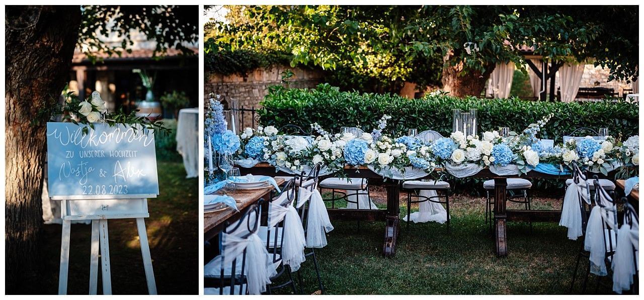 Willkommensschild in blau und weißer Schrift und Tischdekoration in weiß blau mit weiß blauen Rosen bei einer Hochzeit in einer privaten Finka in Kroatien