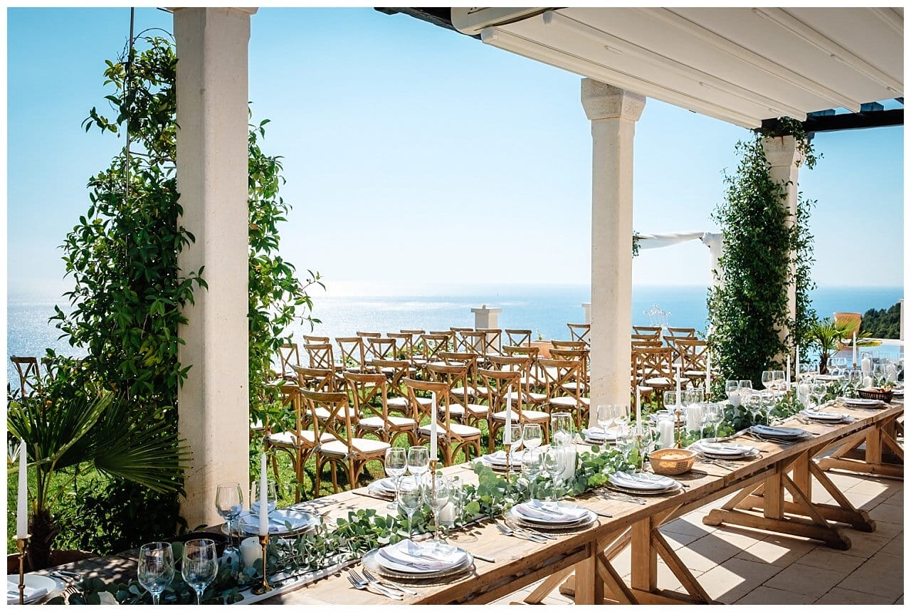Tischdekoration weiß mit grünen blättern und Golden Aktzenten auf einen hell braunen Holztisch mit dem blick aufs Meer bei einer Hochzeit in einer privaten Villa in Kroatien
