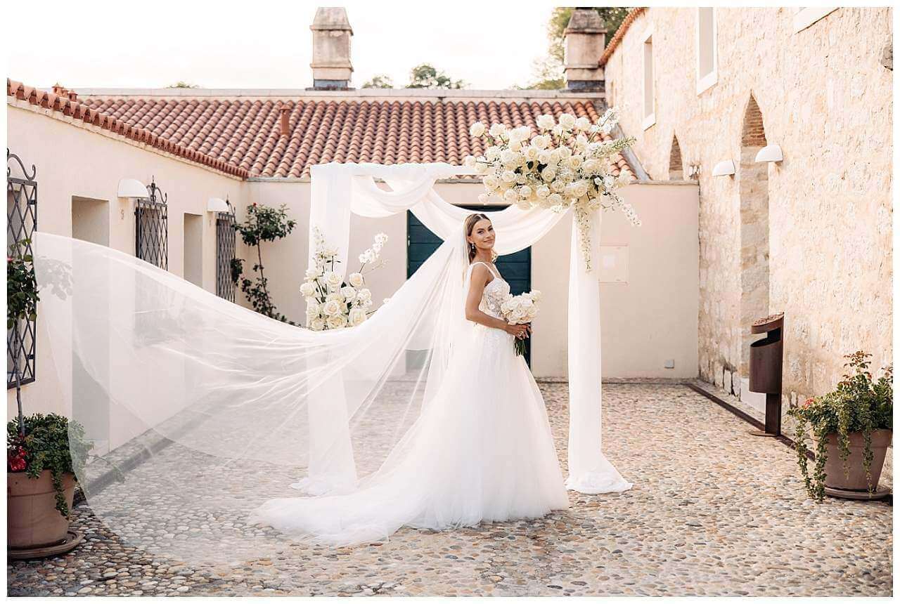 Braut im Traubogen mit wehendem Schleier bei freier Trauung im Kastell in Kroatien