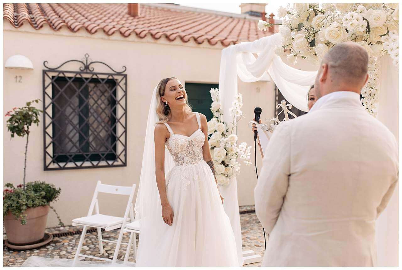 Braut lacht bei Ehegelübde bei Sommerhochzeit im Kastell in Kroatien